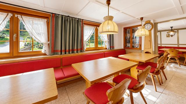 Mühlenstube mit roten Sitzbänken entlang der Fenster und mehreren Tischen